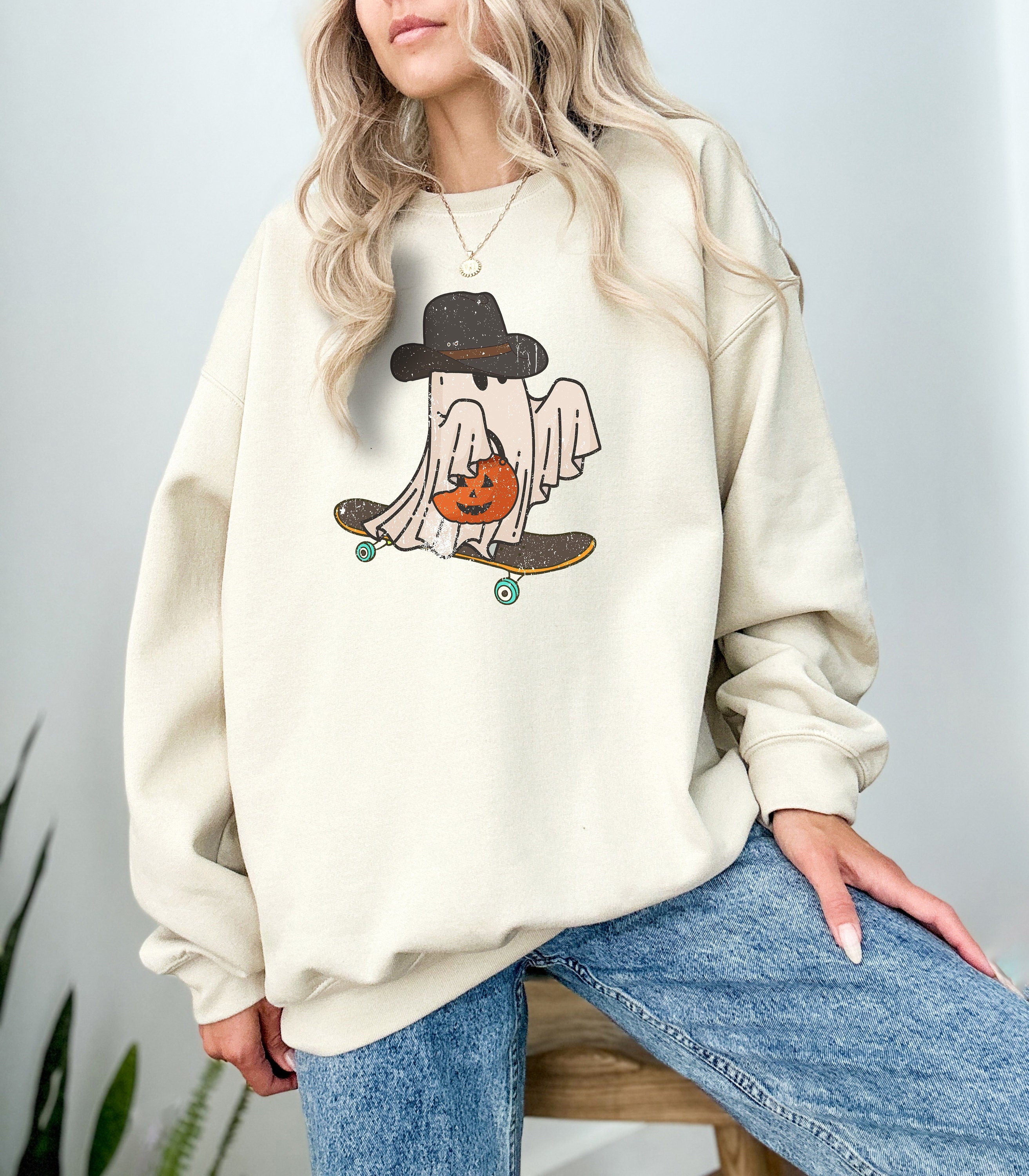 Skate boarding trick or treating ghost with a cowboy hat crewneck sweatshirt